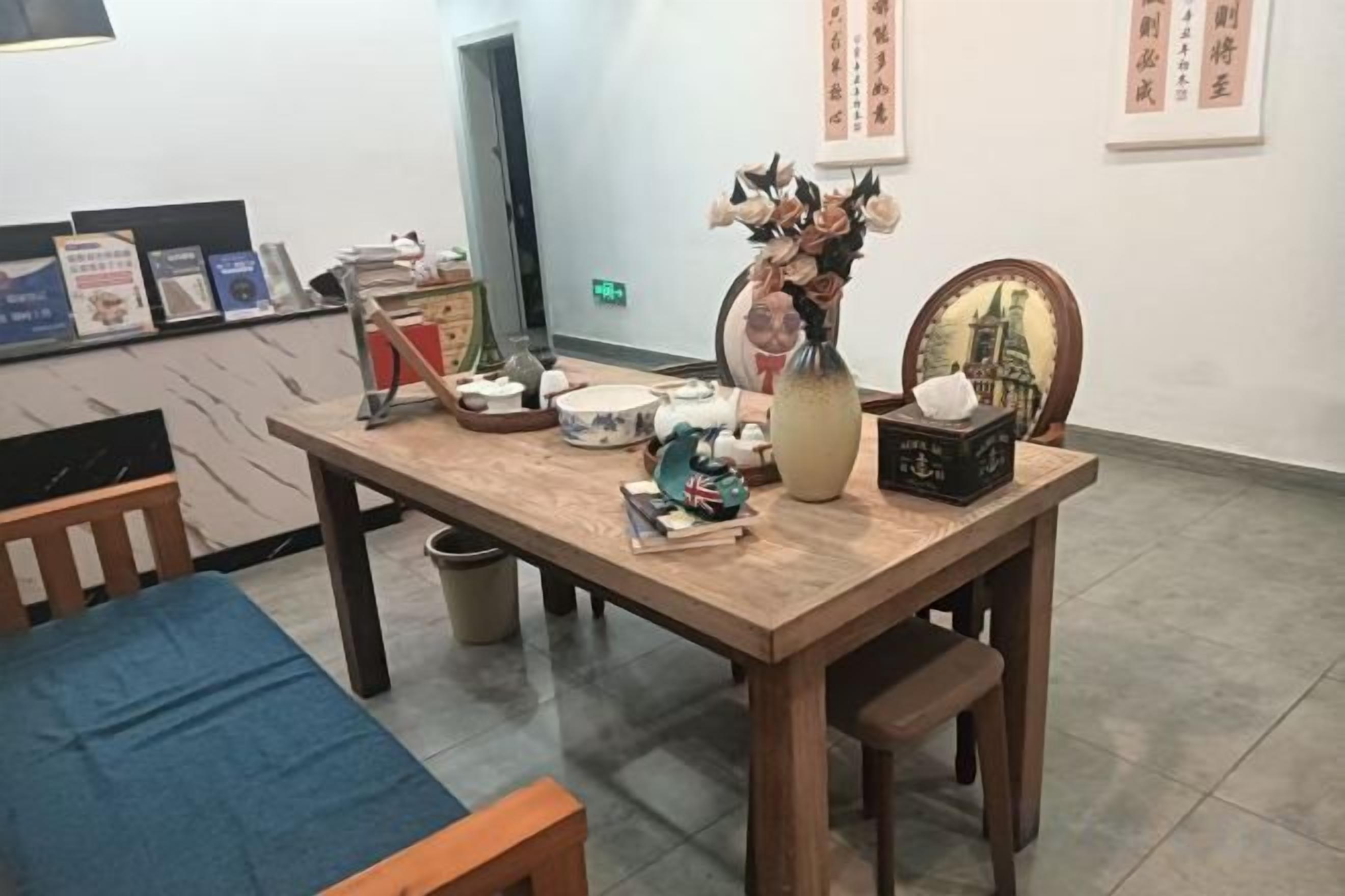A wooden table with various items including a vase, a framed picture, and some books.