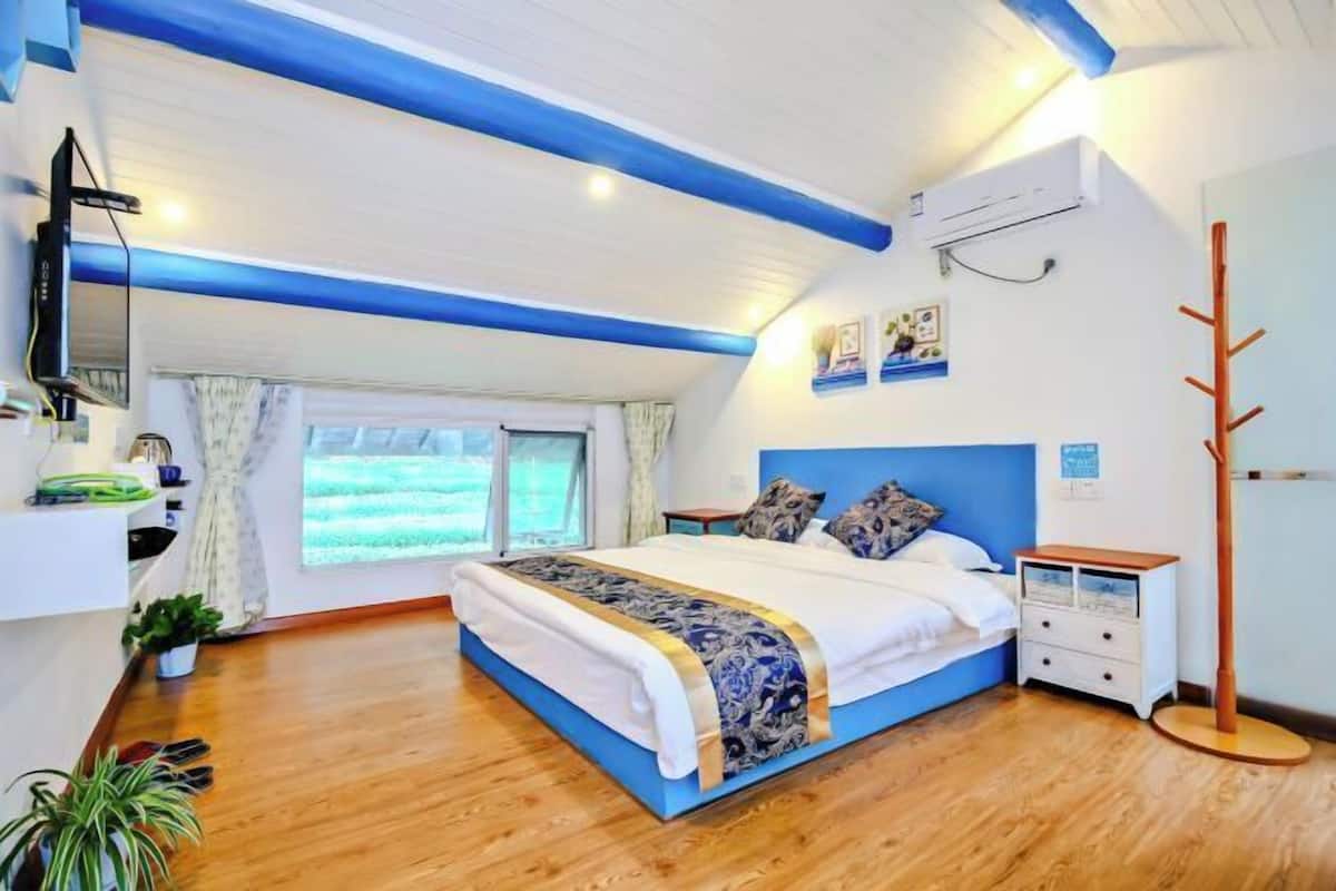 Ein Schlafzimmer mit Bett, Nachttischen, einem Fernseher und einem Fenster.