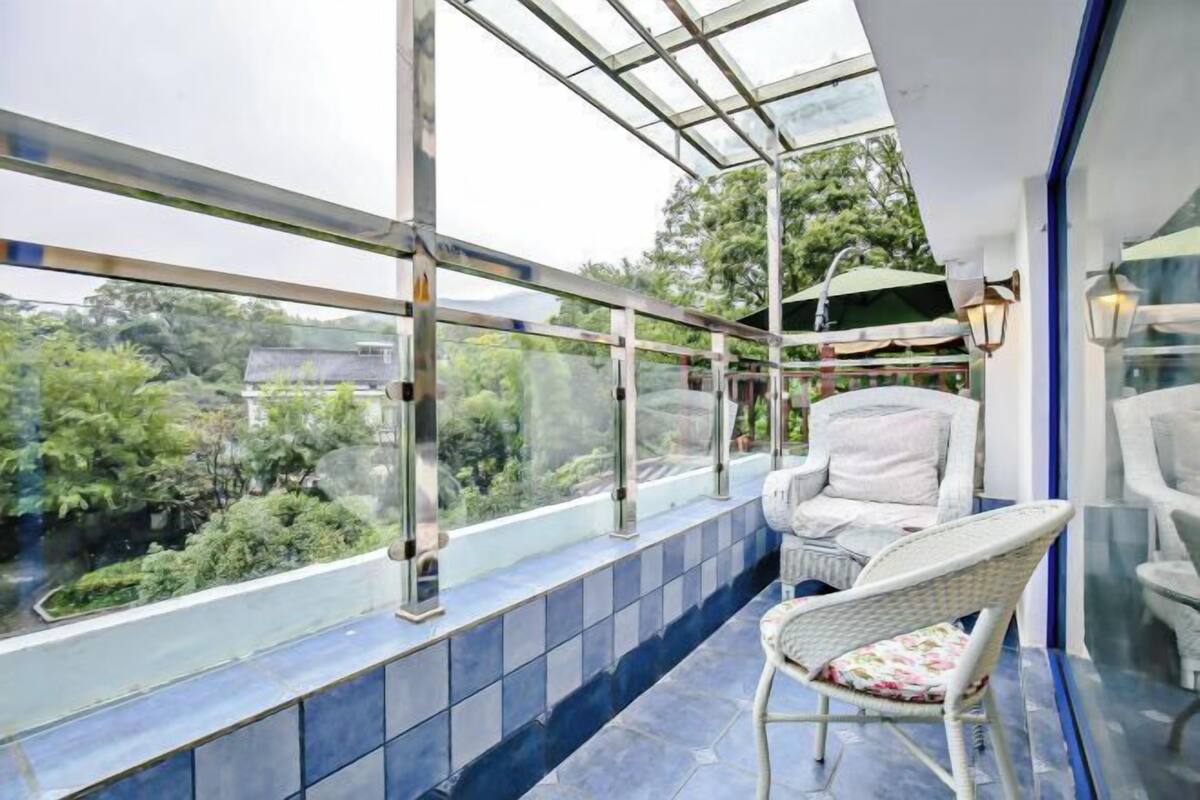 Ein Balkon mit Glasveranda, Korbmöbeln und Blick ins Grüne.