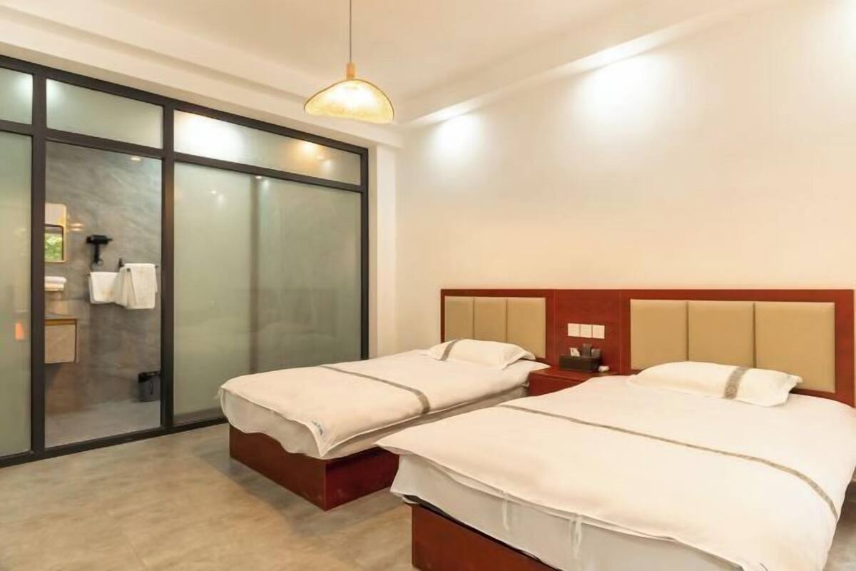 Ein Hotelzimmer mit zwei Betten, einer Schiebetür, einem Nachttisch und einer Pendelleuchte.