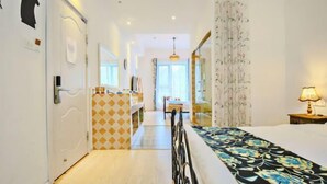 A hotel room with a bed, a desk, a chair, a lamp, and a view of the hallway. - Hangzhou Lanyu Maitian Inn (Xihu Lingyin Branch) (Hangzhou)