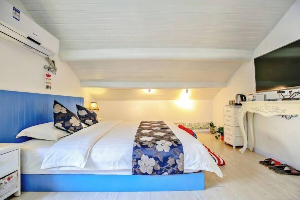 Ein Schlafzimmer mit Bett, Nachttisch, Lampe, Kommode und Fernseher.