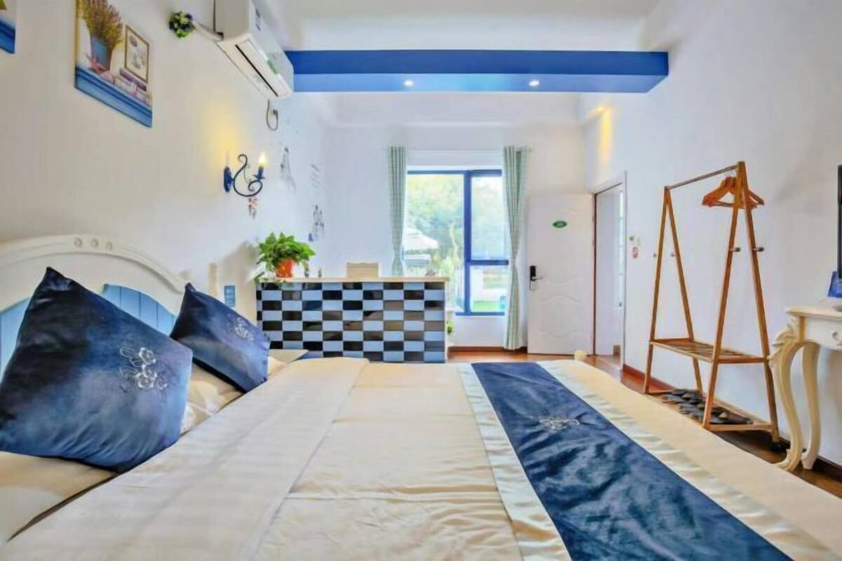 Ein Schlafzimmer mit einem Bett, einem karierten Kopfteil, einer hängenden Pflanze und einem hölzernen Kleiderbügel.