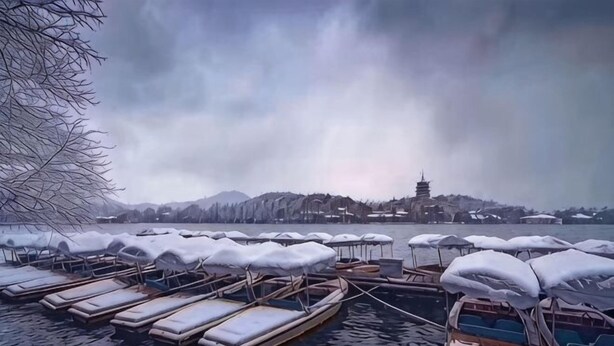 A row of boats with snow-covered roofs docked in a calm body of water, a leafless tree to the left, and a distant pagoda on a hill. - Hangzhou Lanyu Maitian Inn (Xihu Lingyin Branch) (Hangzhou)