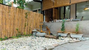 A garden area with a bamboo fence, stone pathway, and potted plants. - Hangzhou Lanyu Maitian Inn (Xihu Lingyin Branch) (Hangzhou)