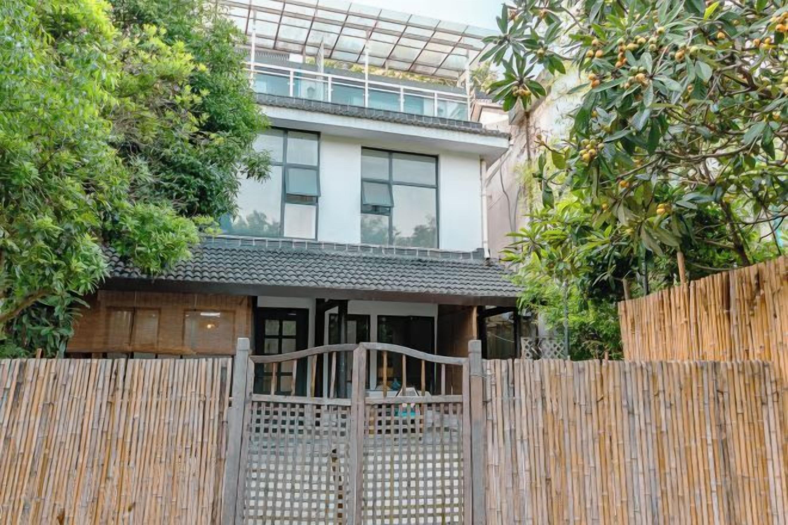 A two-story building with a traditional tiled roof, a wooden fence, and a gate.