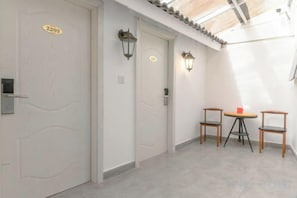 A hallway with two doors, each marked with a number. There are two chairs and a small table with a red object on it. - Hangzhou Lanyu Maitian Inn (Xihu Lingyin Branch) (Hangzhou)