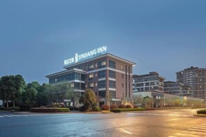 A modern hotel building with a prominent sign, multiple floors, and a well-maintained surrounding area.