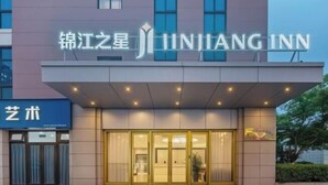 Un hotel con una facciata moderna, un cartello ben visibile con la scritta 'JINJIANG INN' e un ingresso con porte in vetro.