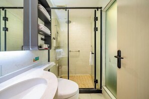 A bathroom with a toilet, sink, and glass shower enclosure. - Jinjiang-Inn Fengshang Wuxi Yuqi Huxi Road Hotal (Wuxi)