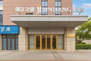 A hotel entrance with a sign reading 'JINJIANG INN' and a smaller sign to the left that says 'Art'. - Jinjiang-Inn Fengshang Wuxi Yuqi Huxi Road Hotal (Wuxi)