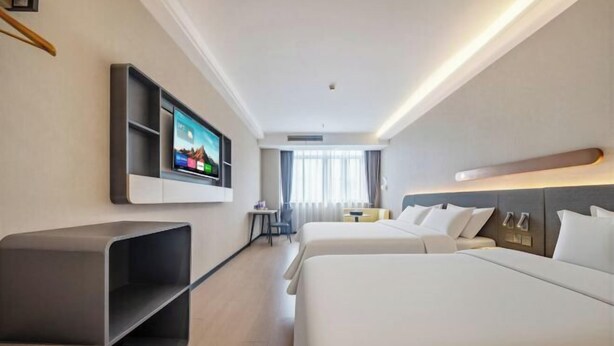 Camera d'albergo con due letti, una televisione a parete, un tavolino e una sedia.