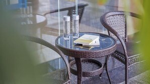 Mesa de vidrio redonda con dos sillas, un libro y dos saleros.