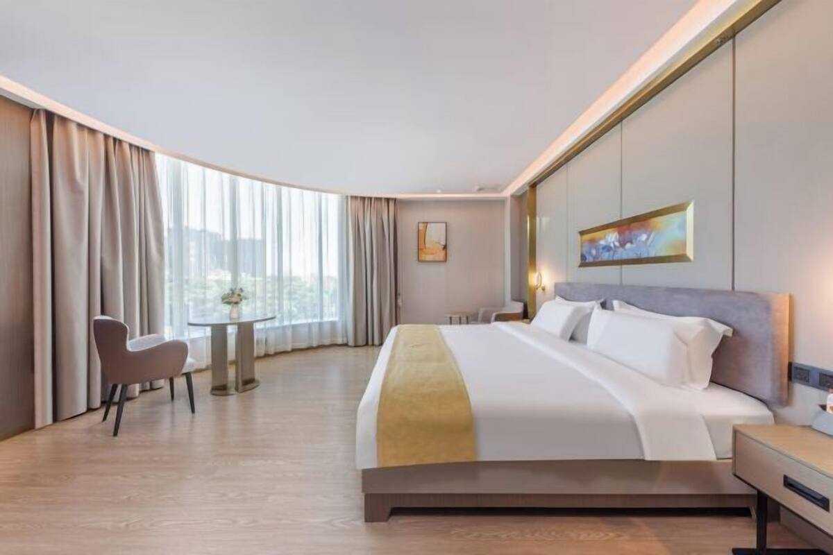 Een hotelkamer met een bed, een stoel, een klein tafeltje en een schilderij aan de muur.