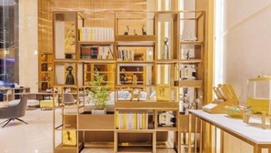 Una biblioteca moderna con estanterías de madera, una máquina de café blanca y una zona de estar con sillones.
