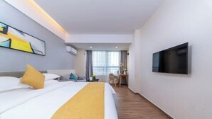 Habitación de hotel con una cama grande, un escritorio, una silla, un televisor montado en la pared y una ventana con cortinas.