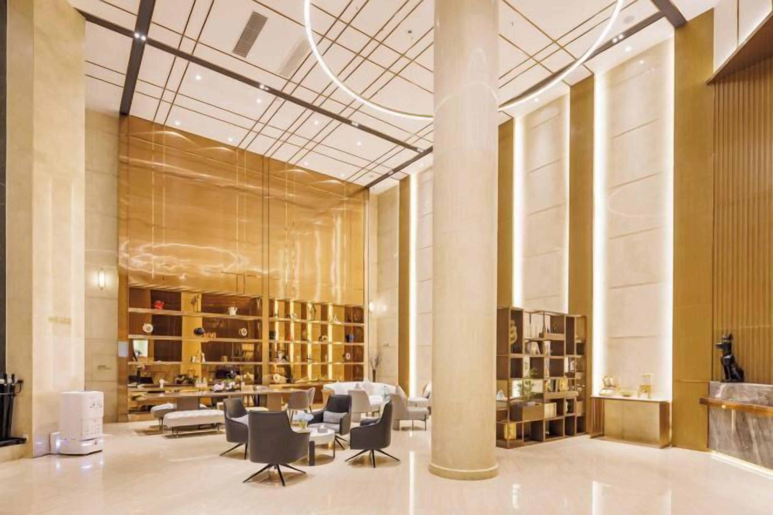 A spacious lobby with a high ceiling, large columns, and a central seating area with sofas and tables.