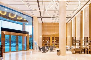 A spacious lobby with a high ceiling, large windows, and a central column.