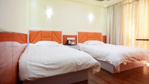 Habitación de hotel con dos camas, una mesita de noche y una ventana con cortinas.