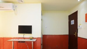Una habitación con televisor sobre un mueble, una puerta y un aire acondicionado instalado en la pared.