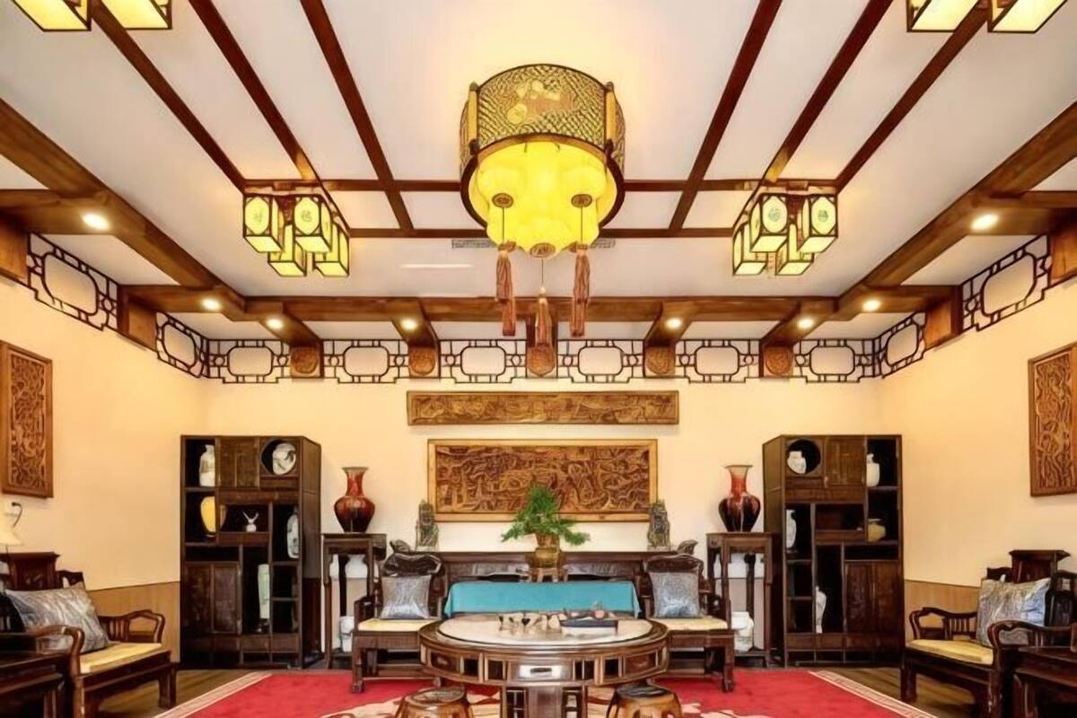 A traditional room with a round table, sofas, and a chandelier.