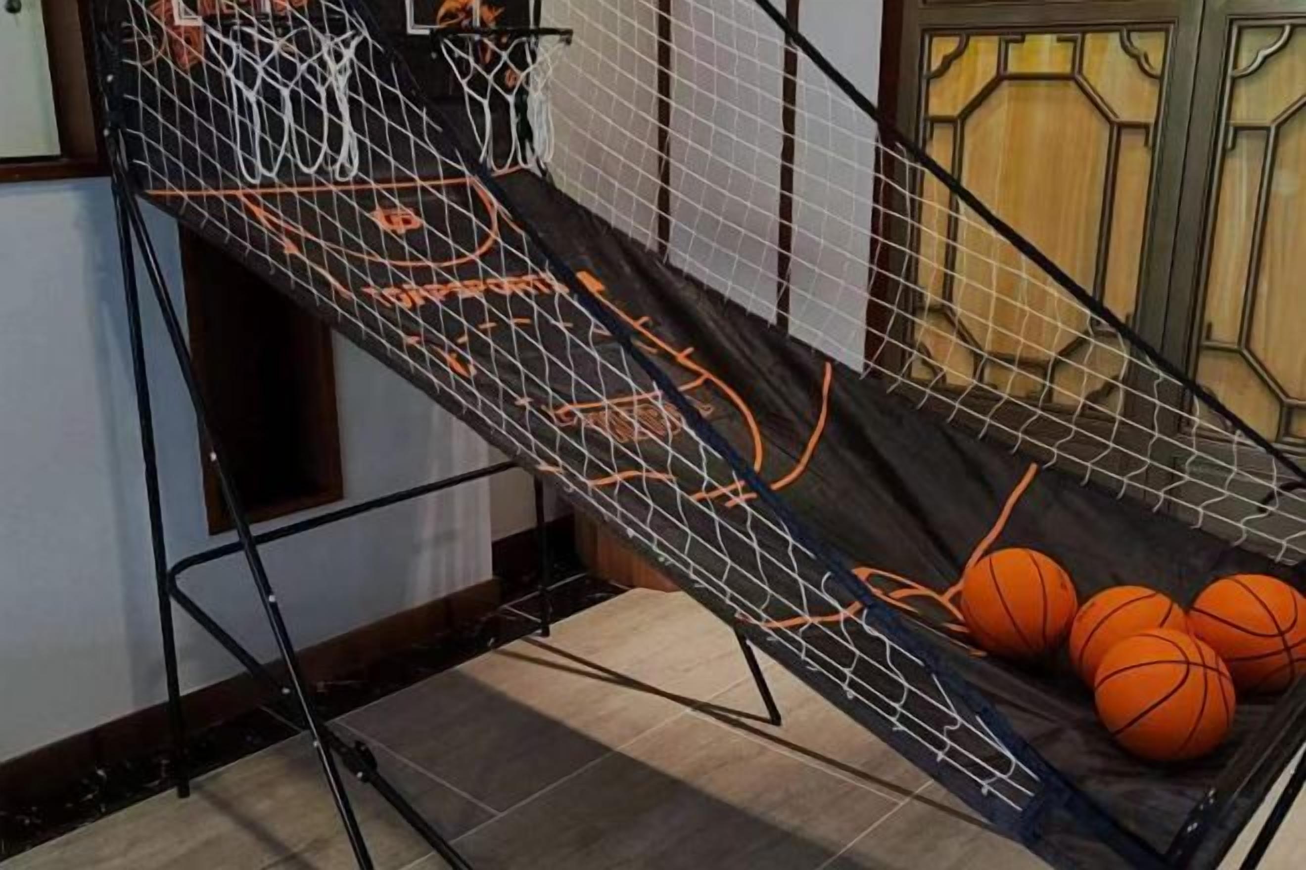 A basketball court with a net and balls, a staircase, and a door with a geometric design.