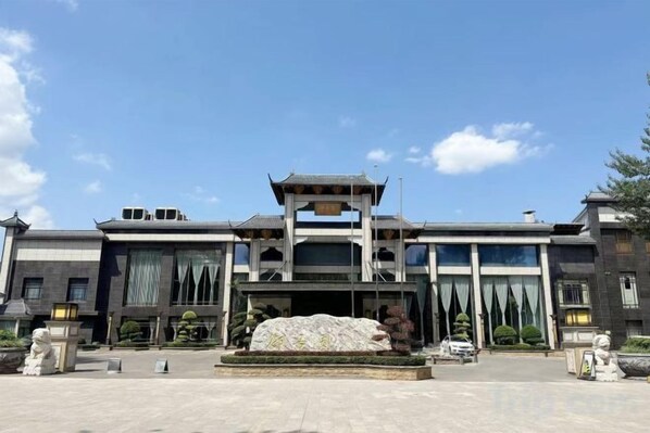 A modern building with a central entrance, large windows, and a stone feature in the foreground. - Yujing Garden Holiday Hotel (Shijiazhuang)