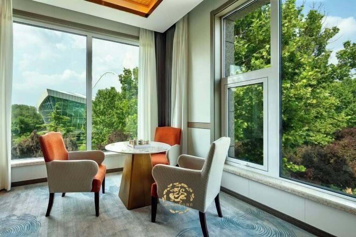 A modern room with large windows, a round table, and two chairs.