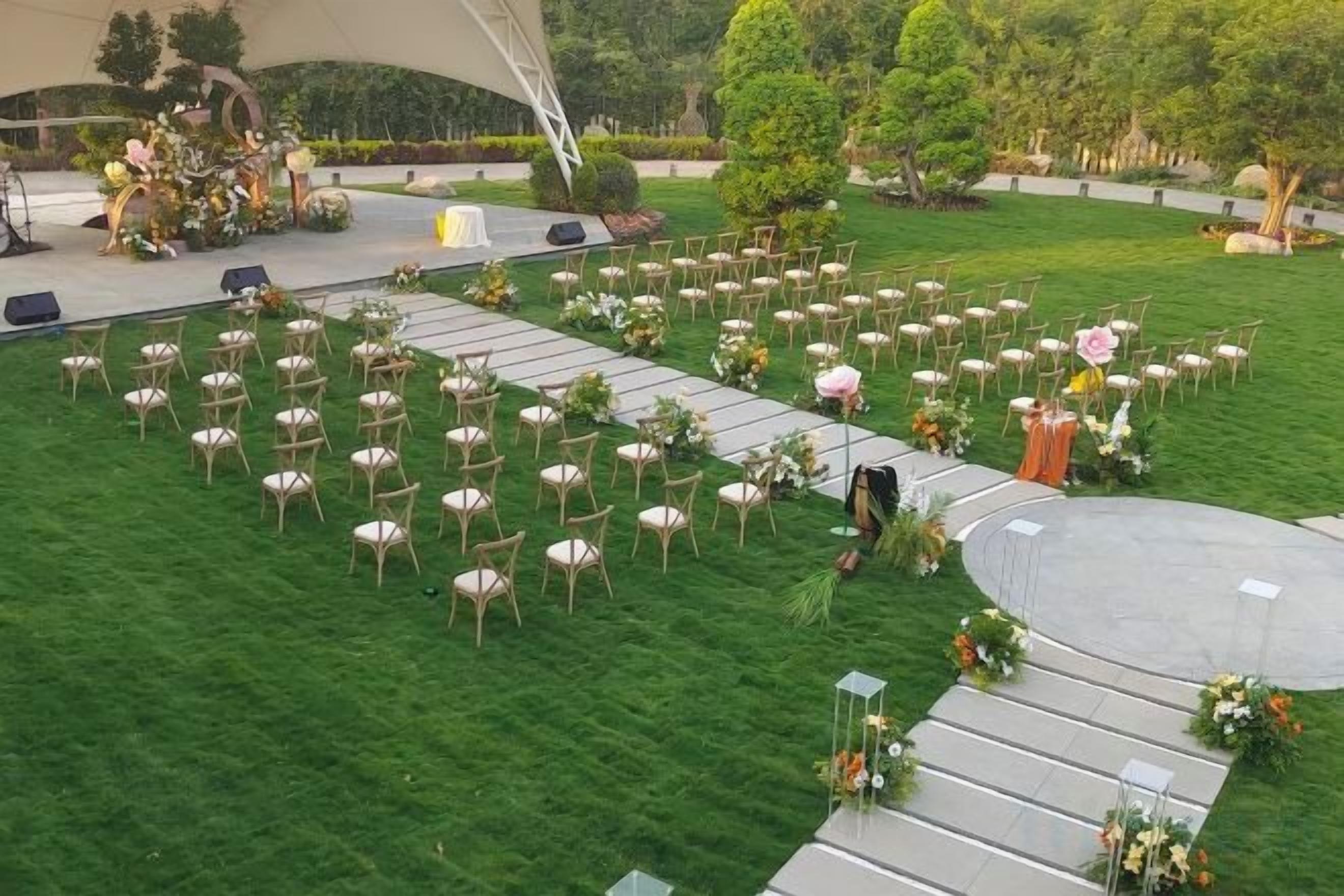 An outdoor wedding venue with rows of chairs and a stage.
