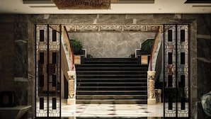 Ein prächtiger Eingangsbereich mit einer Marmortreppe, einem verzierten Tor und einem Blumentopf im Treppenhaus.