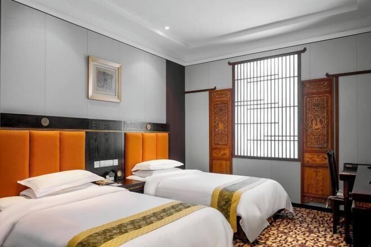 A hotel room with two beds, a window with bars, and traditional decor.