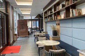 A hallway with seating, a bookshelf, and a red mat. - Yujing Garden Holiday Hotel (Shijiazhuang)