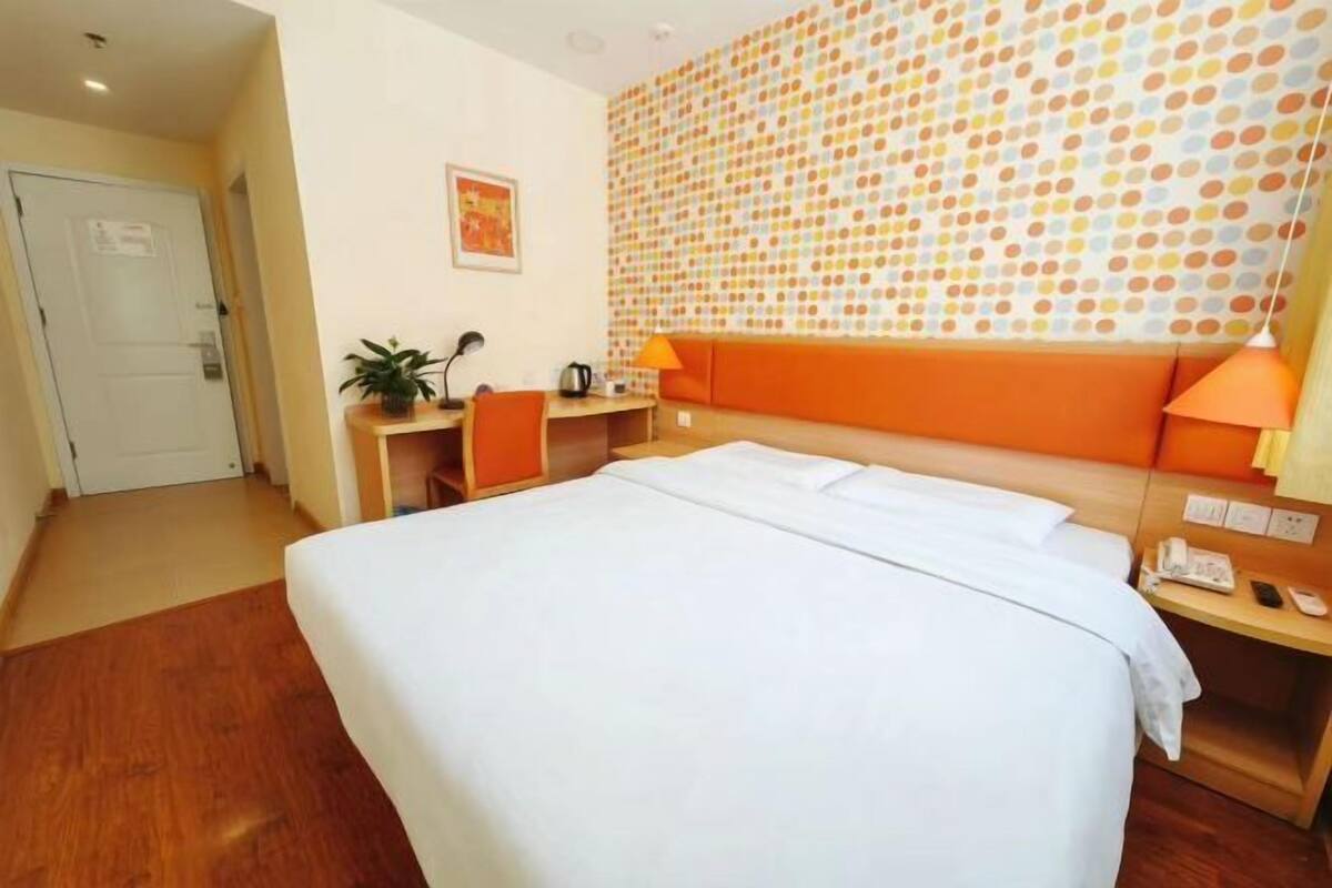 Habitación de hotel con cama, escritorio, silla y pared con estampado de lunares.