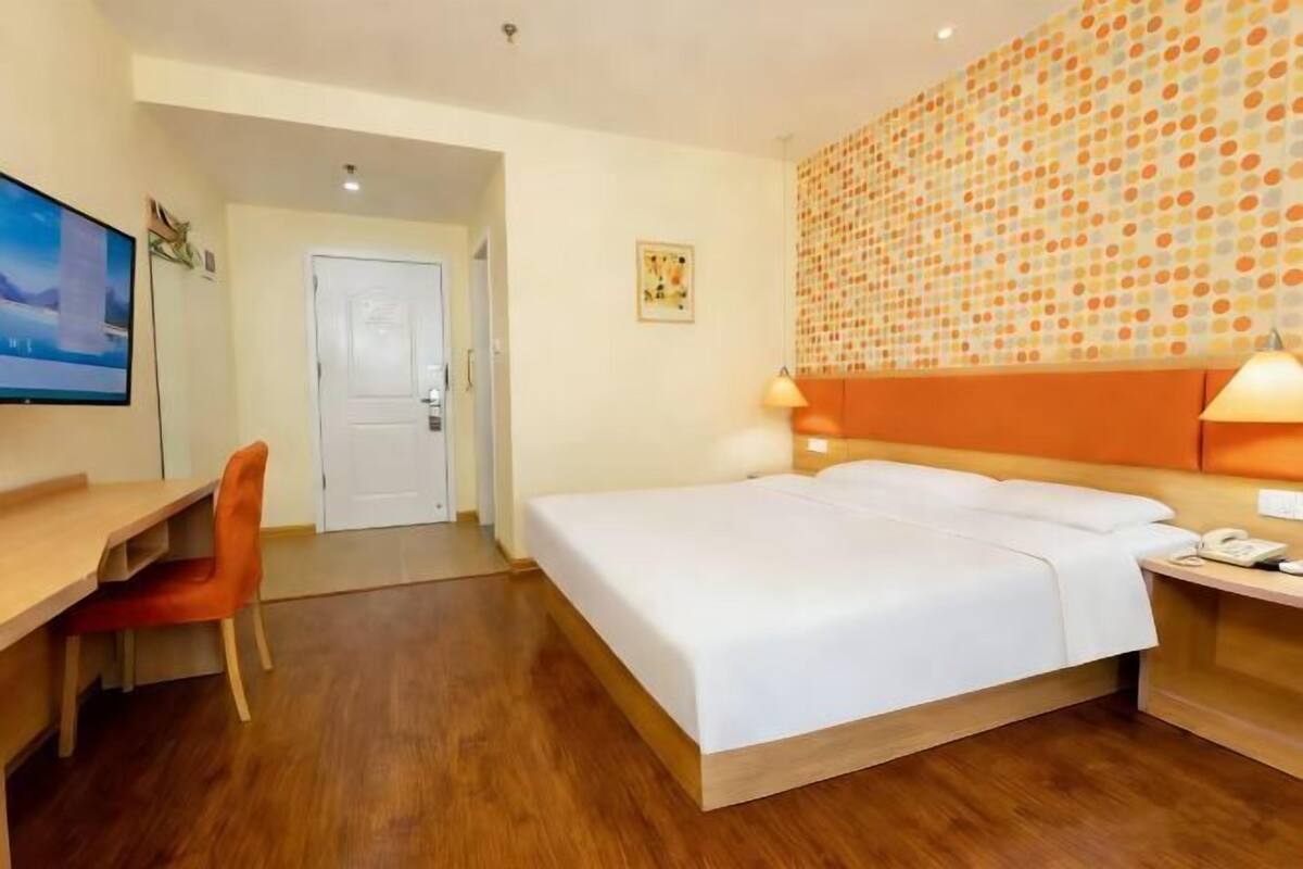 Habitación de hotel con cama, escritorio, silla y pared con estampado de lunares.