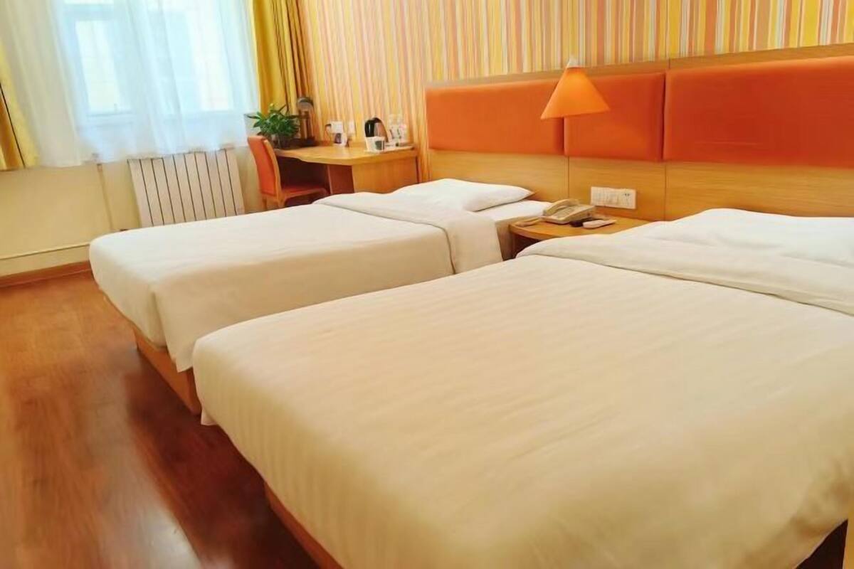 Habitación de hotel con dos camas, un escritorio, una lámpara y un teléfono.
