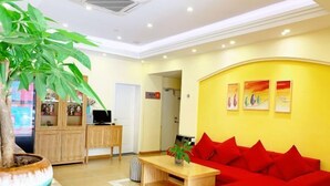 Una sala de estar moderna con un sofá rojo, una mesa de centro de madera y una planta grande en maceta.