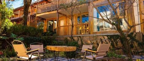 A wooden house with a balcony, outdoor seating, and a garden.