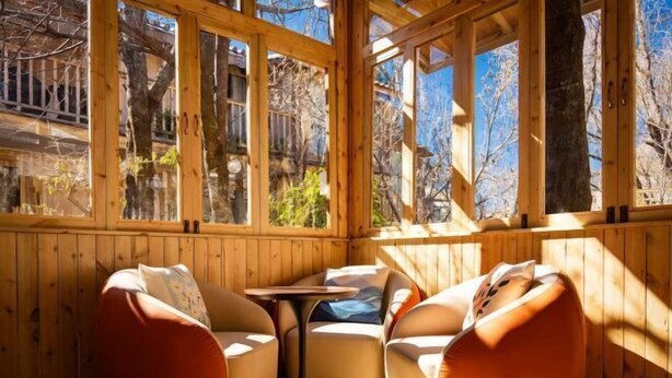 A wooden cabin with large windows, a small table, and two bean bag chairs. - Hengchangbao Garden Pinsu Lvyexianzongyulin Guanjing Inn (Lijiang)