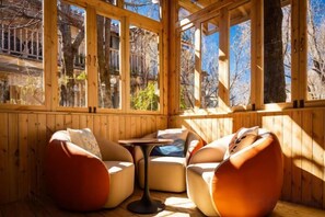 A wooden-paneled room with two sofas and a small table, large windows, and a view of trees.