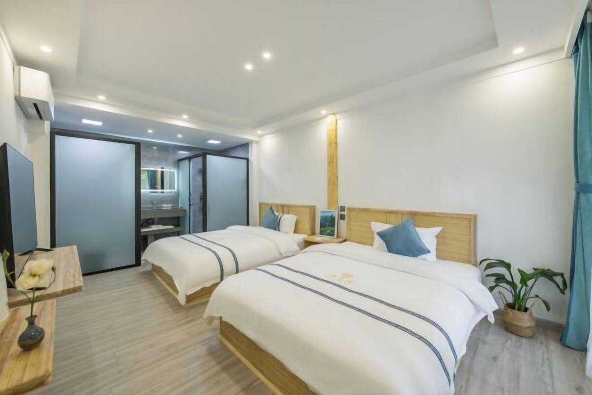 Ein Hotelzimmer mit zwei Betten, einem Spiegel, einem kleinen Tisch und einer Zimmerpflanze.