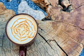A cup of coffee with latte art on a wooden surface. - Hengchangbao Garden Pinsu Lvyexianzongyulin Guanjing Inn (Lijiang)