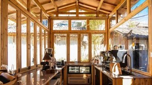 A compact kitchen with wooden beams, a central island, and a window overlooking a snowy landscape. - Hengchangbao Garden Pinsu Lvyexianzongyulin Guanjing Inn (Lijiang)