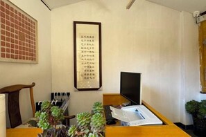 A room with a desk, a computer, a framed calligraphy piece, and a potted plant. - Hengchangbao Garden Pinsu Lvyexianzongyulin Guanjing Inn (Lijiang)