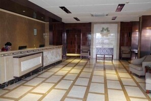 A reception area with a marble floor, a reception desk, and a seating area with chairs.