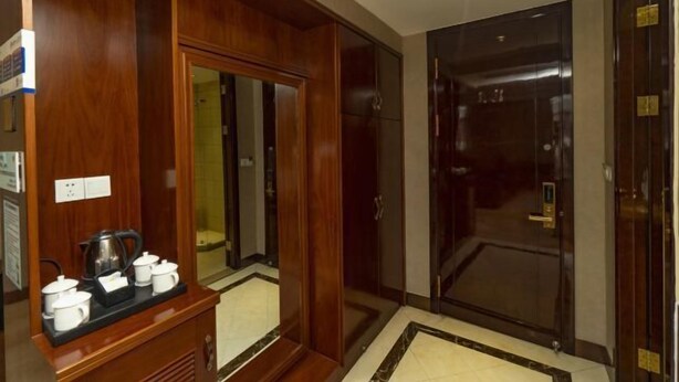 Ein Hotelzimmer mit einem Holzschrank, einer Kaffeestation und einer Glastür zum Badezimmer.