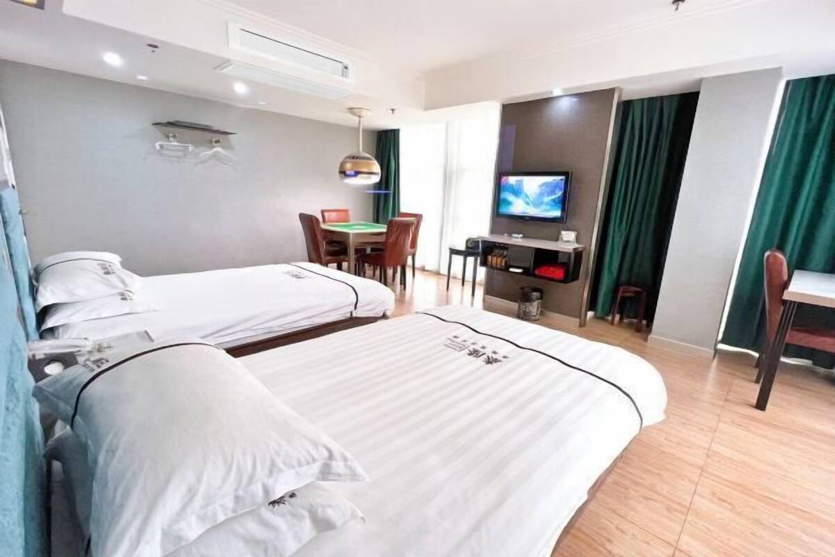 Habitació d'hotel amb dos llits, un escriptori amb televisió, una taula de menjador i una cadira.
