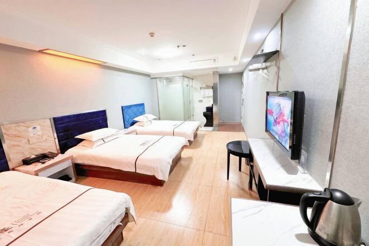Habitació d'hotel amb dos llits, televisió, escriptori i una tetera.