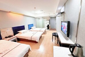 Een hotelkamer met twee bedden, een televisie, een bureau en een waterkoker.