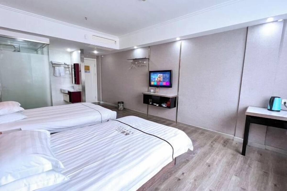 Habitació d'hotel amb dos llits, televisió, taula petita i mirall.