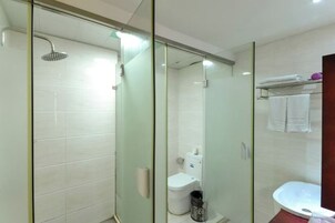 Un baño moderno con ducha de vidrio, inodoro y lavamanos.